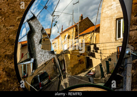 Reflection of a stone house in a broken street mirror, france Stock Photo