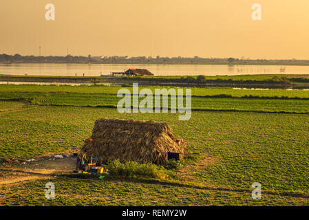 Burmese woman draws water from a well at sunset in Mandalay, Myanmar Stock Photo