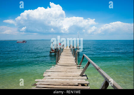 Bright scenic view of a rickety old wooden dock on the tropical shore of a beach in Bahia, Brazil Stock Photo