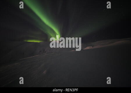 Northern Lights, Skiing And Hiking In Snowy Winter Mountains At Night Under The Moon, The stars And The Beautiful Northern Lights. Stock Photo