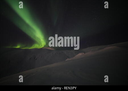 Northern Lights, Skiing And Hiking In Snowy Winter Mountains At Night Under The Moon, The stars And The Beautiful Northern Lights. Stock Photo