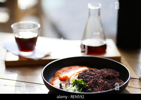 Vegan black rice cutlets served with orange carrots mesh and microgreeens and decaf coffee. Vegeterian food hipster cafe. Stock Photo
