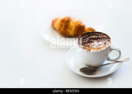 Cappuccino coffee with foam in whilte cup and croissant isolated on white table background Stock Photo