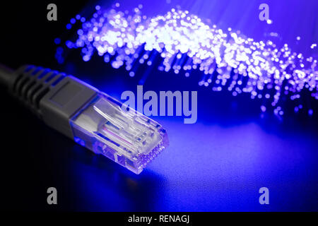 Glowing fiber optic cable and connector RJ-45 on a dark background. Modern communications Abstract hi-tech background. Stock Photo