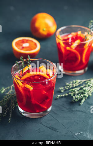 Red orange juice in a large glass ore Blood Orange Sparkling Vodka cocktail on dark concrete background, copy spice, shallow depth of the field. Stock Photo