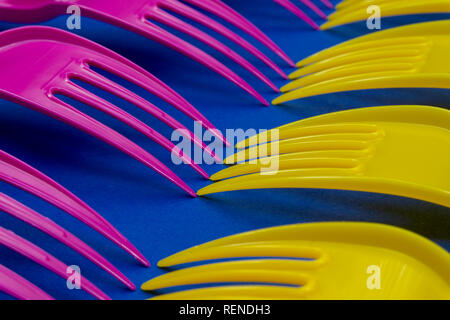 Yellow and pink cutlery plastic forks arranged on blue background. Color trends and plastic waste problem concept Stock Photo