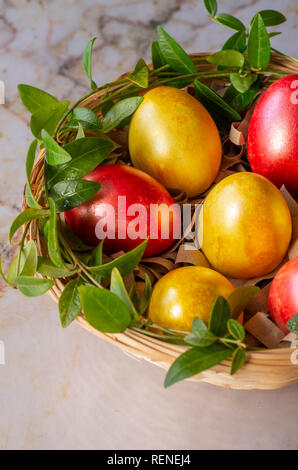 Easter eggs in the basket. Easter eggs on marble background. A sprig of greenery. Stock Photo
