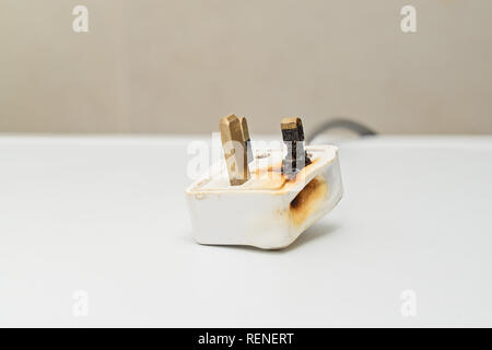 Burned 250V uk style socket and converter. Improper use of AC Power Plugs and Sockets cause of short circuit and fires at home, selective focus Stock Photo