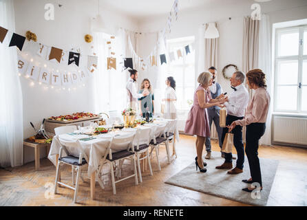 Multigeneration family with presents on a indoor birthday party. Stock Photo