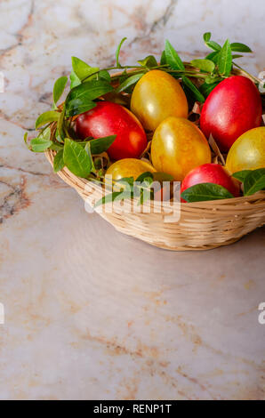 Easter eggs in the basket. Easter eggs on marble background. A sprig of greenery. Top view with copy space. Stock Photo