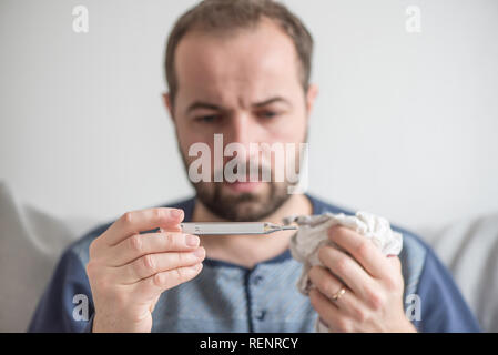 Man checks the body temperature with a mercury thermometer. Theme of viral diseases, flu, colds.
