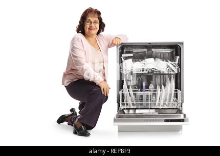 Elderly woman with an open loaded dishwasher isolated on white background Stock Photo