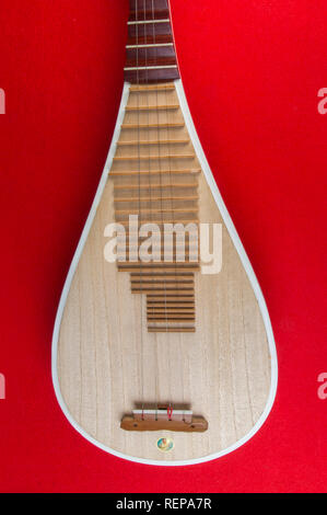 Pipa Chinese guitar, four-stringed lute with 30 frets and pear-shaped body, on red background Stock Photo