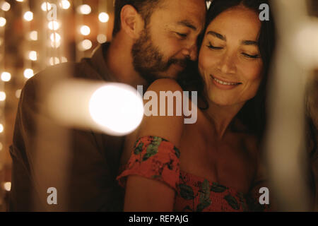 Couple in love hugging and enjoying an intimate moment together, against the backdrop of lights. Couple doing a romantic dance. Stock Photo