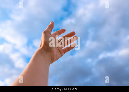 Woman's hand reaching to towards blue sky. Stock Photo