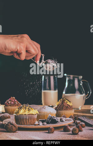 Fresh muffins and cupcakes sprinkled with sugar on a wooden board - Image Stock Photo
