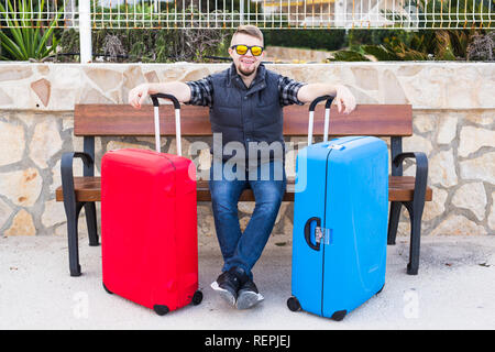 Travel, tourism and people concept - happy man sitting on a bench with two suitcases, he is ready for travelling Stock Photo