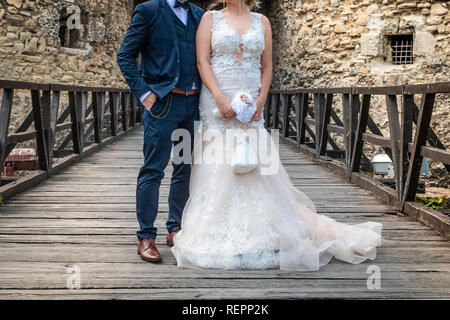 Wedding couple stand on the wooden bridge in the front of old fortress. Stock Photo