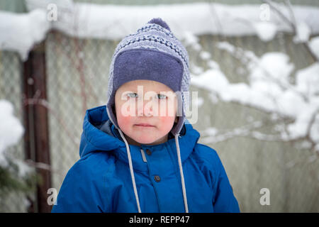 Portrait of a little boy in a winter hat and jacket while walking on a cold winter snowy day Stock Photo