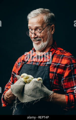 happy old farmer holding a cloth with chickens Stock Photo