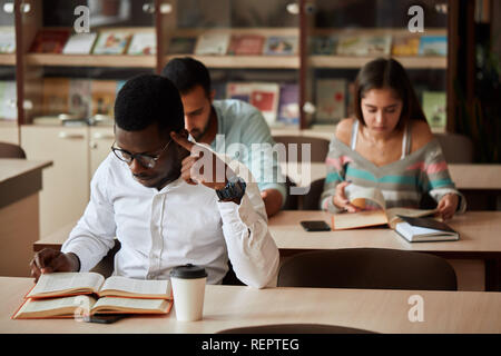 African american male college studen preparing for exams in the library. Stock Photo