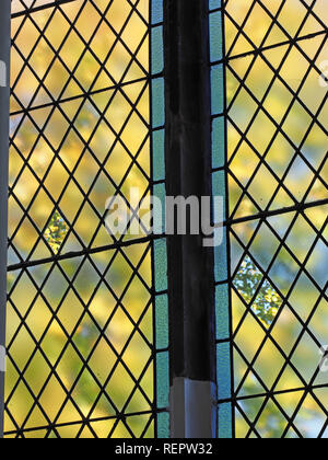 isolated plain glass panels among frosted glass leaded panes in upright mullioned window give clarity to yellow green foliage in Cumbria, England, UK Stock Photo