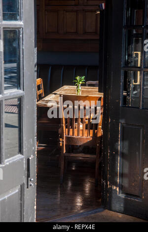 sunlight on wooden table and chairs seen through open doors Stock Photo