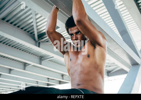 Athletic man doing pull ups during an outdoor workout Stock Photo