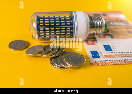 Led Light Bulb and european banknotes and coins. E27 Corn bulb Stock Photo