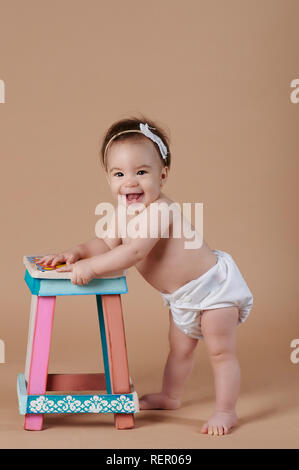 Wide smiling pretty baby girl on brown studio background Stock Photo