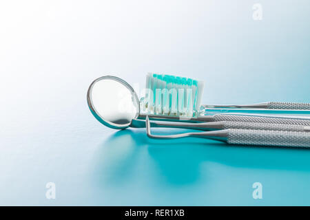 Dental instruments. Dentists tools and toothbrush on blue background. Stock Photo