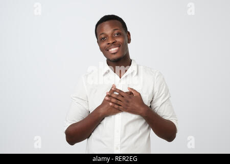 Happy friendly african man being content to hear compliment, expresses his gratitude and thanks Stock Photo