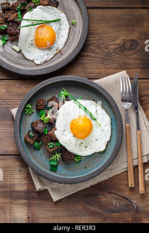 Sunny side fried egg with croutons and herbs, close view Stock Photo