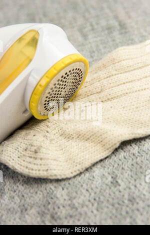 Removing sheaving lint fuzz from white woolen socks, wool clothes maintain concept. Stock Photo