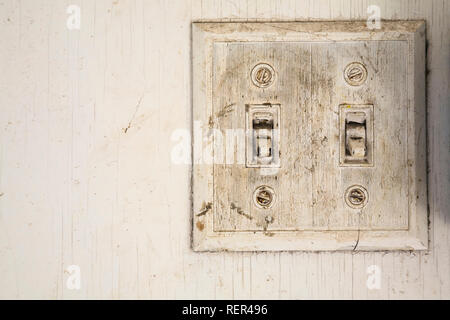 Close-up of old and dirty double On and Off electrical wall switch and white plaque on white wooden wall inside an old barn Stock Photo