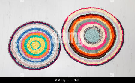 Colorful crochet rug from repurposed T-shirts at white wooden home floor. Flat lay view. Stock Photo