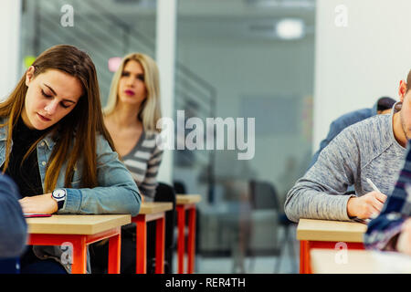 Students sitting in an exam hall doing an exam in university Stock Photo