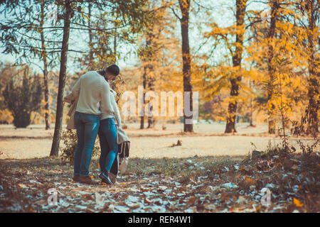 Urban couple is taking a walk in the wood, looking happy and kissing Stock Photo