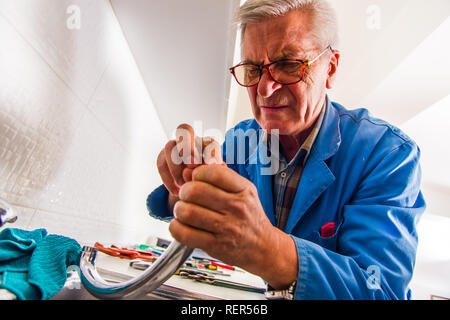 Professional handyman is fixing the kitchen faucet with his tools Stock Photo