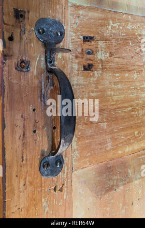Close-up of antique metal door handle on distressed wooden closet door inside an old 1809 French regime cottage style home Stock Photo