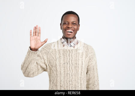 Polite young African American man dressed in sweater saying hi Stock Photo