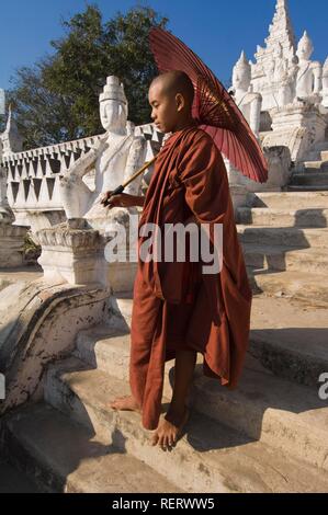 Young Buddhist monk with a red umbrella, Settawya Pagoda, Mingun, Burma, Myanmar, South East Asia Stock Photo