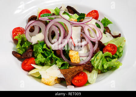 Salad of lettuce, tomatoes, chanterelles, croutons and onions with parmesan and olive oil. Close-up Stock Photo