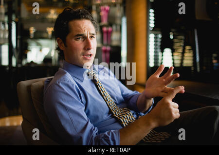 Young businessman explaining while sitting inside a bar. Stock Photo