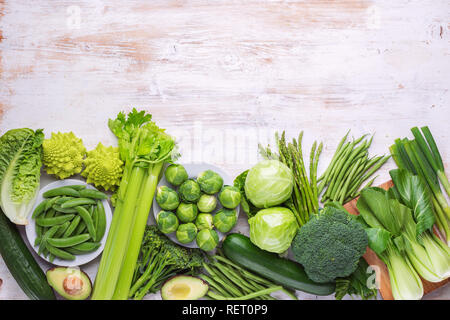 Healthy eating vegan concept. Green vegetables on white table broccoli sprouts peas avocado courgette beans bok choy celery, top view, copy space Stock Photo