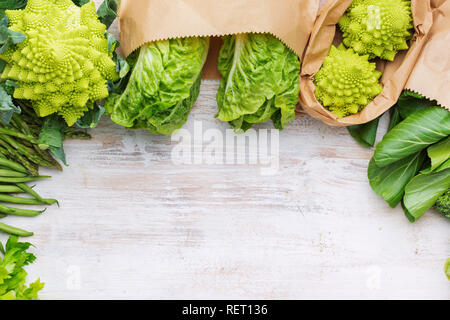 Healthy eating, copy space. Farmers market produce in paper bags. Green vegetables on white table, broccoli sprouts peas avocado courgette celery bok  Stock Photo