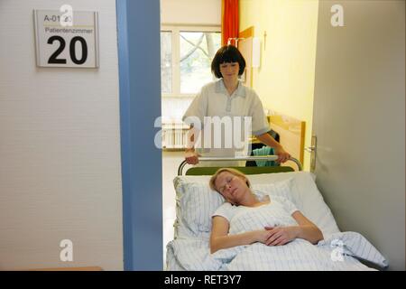 Nurses pushing a patient in a hospital bed through the corridor of a hospital Stock Photo