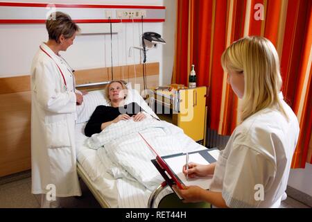 A female doctor talking to a patient in a hospital bed Stock Photo