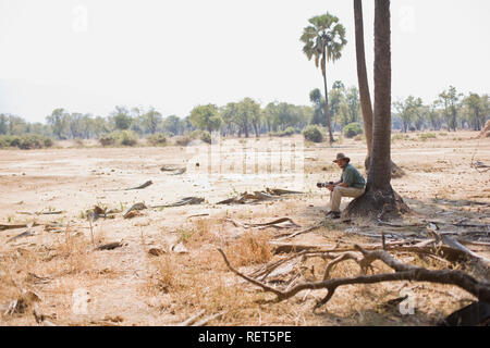 Young adult man sitting under a tree in the Highveld. Stock Photo