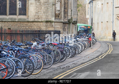 Bicycles parked  in an orderly line on Magdalen Street East outside the church of St Mary Magdalen and opposite an exterior wall of Balliol college. Stock Photo